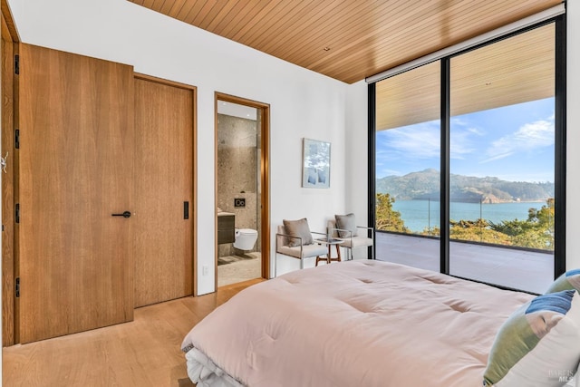 bedroom with a water and mountain view, expansive windows, access to exterior, light hardwood / wood-style floors, and wood ceiling