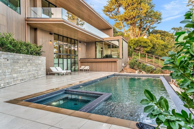 view of pool with an in ground hot tub, exterior bar, and a patio area