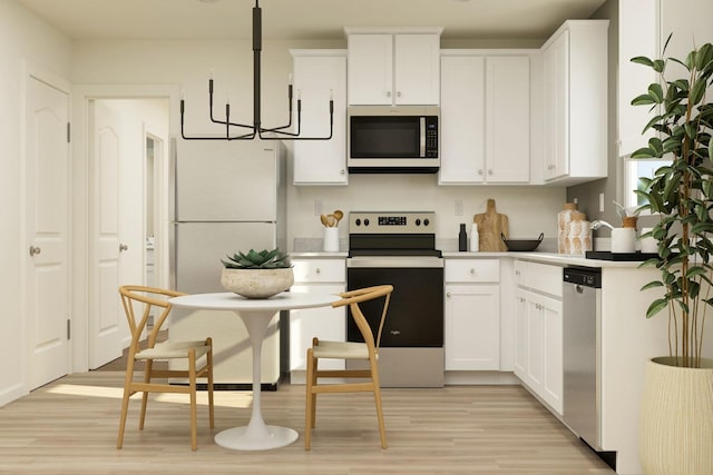 kitchen with an inviting chandelier, light wood-style flooring, light countertops, white cabinets, and appliances with stainless steel finishes