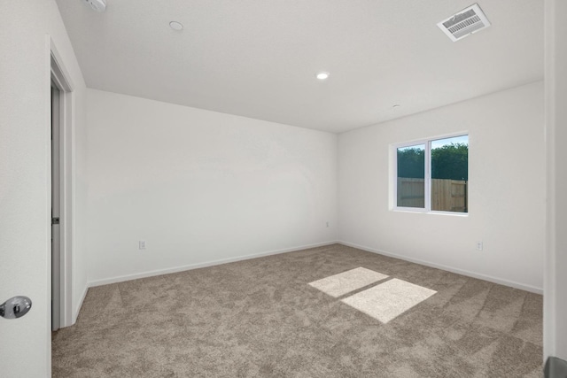 empty room featuring carpet, visible vents, and baseboards