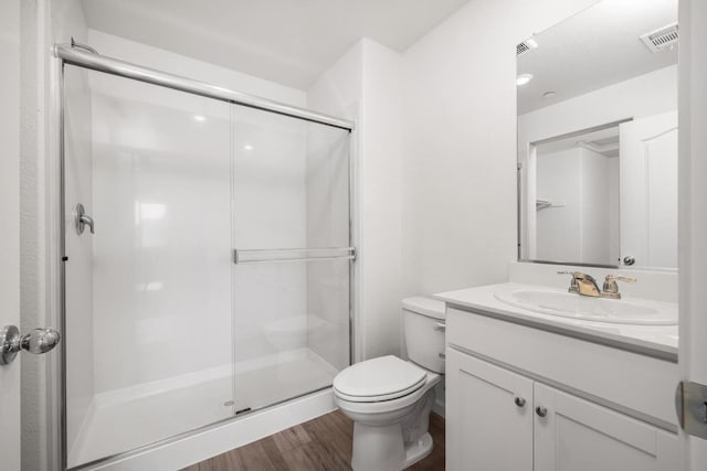 bathroom with visible vents, toilet, a shower stall, and wood finished floors