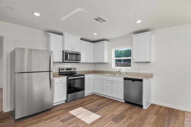 6509 Jackpot Pl, Riverbank, CA 95367 - kitchen with appliances with stainless steel finishes, a sink, white cabinets, light wood finished floors, and recessed lighting