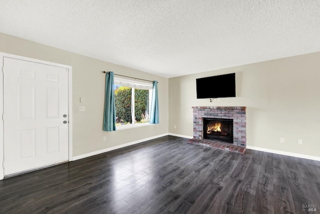 unfurnished living room with dark hardwood / wood-style flooring, a brick fireplace, and a textured ceiling