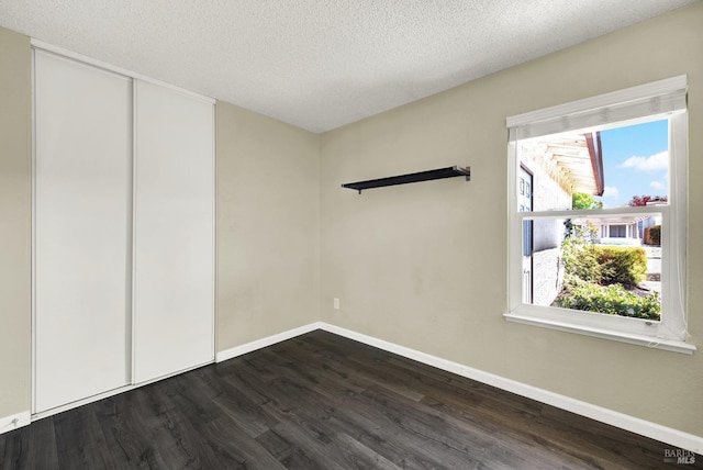 unfurnished room featuring dark hardwood / wood-style flooring and a textured ceiling