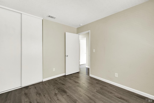 unfurnished bedroom featuring dark hardwood / wood-style floors and a closet