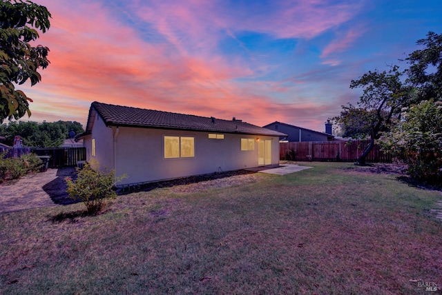 back house at dusk featuring a yard