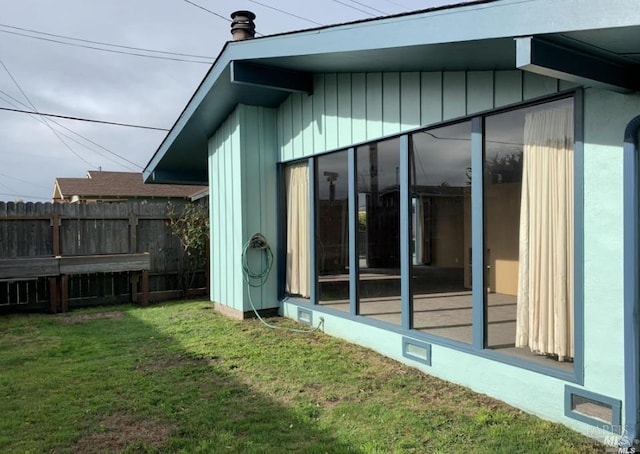 view of home's exterior featuring a sunroom and a lawn