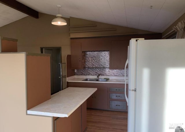 kitchen featuring sink, vaulted ceiling with beams, tasteful backsplash, wood-type flooring, and white fridge