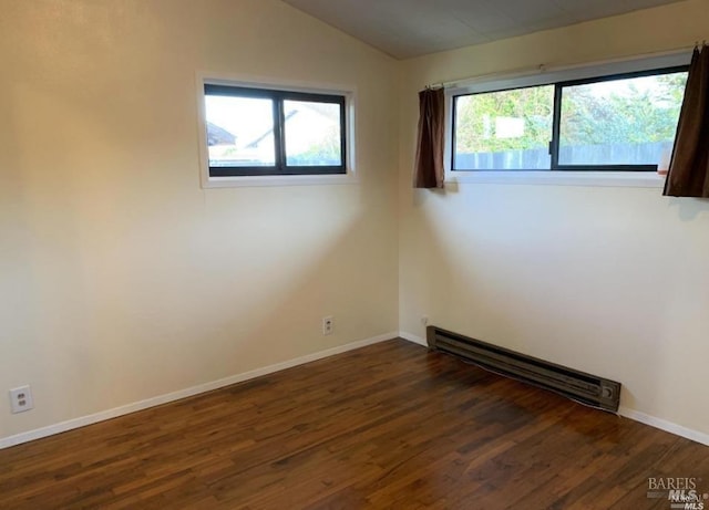 spare room with a baseboard radiator, vaulted ceiling, and dark wood-type flooring