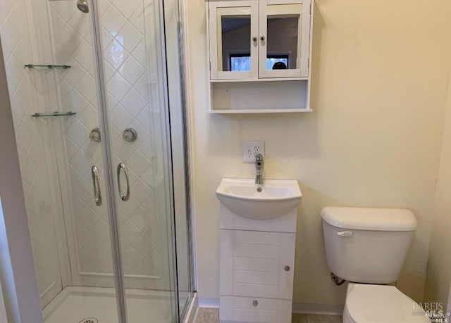 bathroom with a shower with door, vanity, and toilet