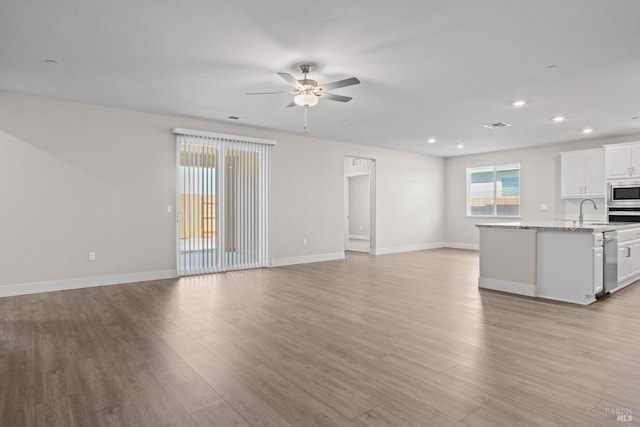 kitchen with light wood-type flooring, open floor plan, white cabinetry, stainless steel appliances, and ceiling fan