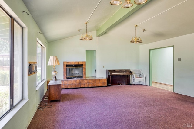 unfurnished living room with carpet floors, a tile fireplace, vaulted ceiling with beams, and an inviting chandelier