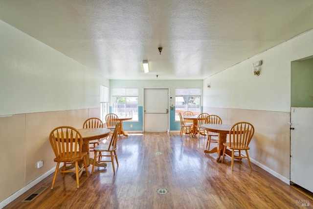 dining area with visible vents, a textured ceiling, baseboards, and wood finished floors