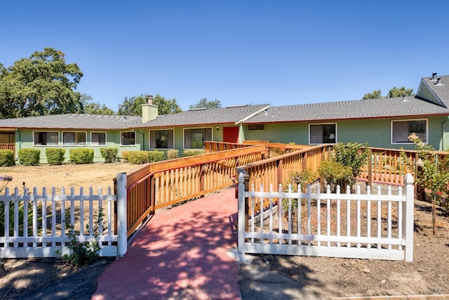 ranch-style home with a deck, fence, a chimney, and stucco siding