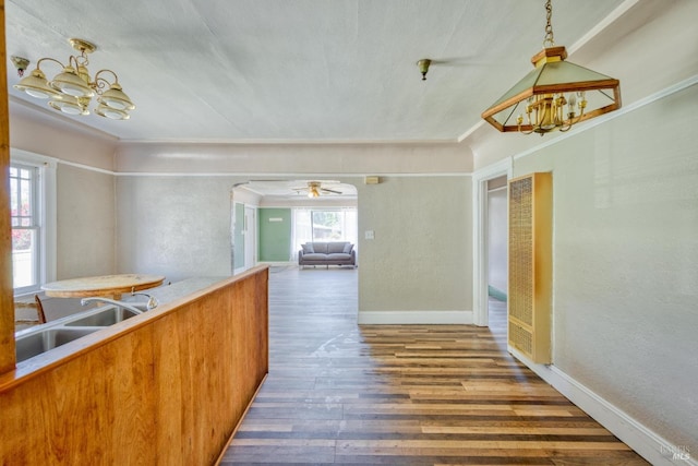 kitchen featuring baseboards, wood finished floors, hanging light fixtures, a chandelier, and a sink