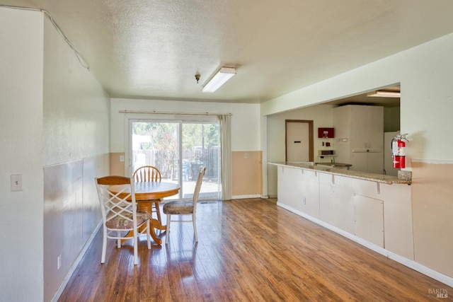 dining area with a textured ceiling, baseboards, and wood finished floors