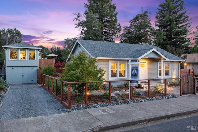 view of front facade featuring a fenced front yard, a gate, roof with shingles, and driveway