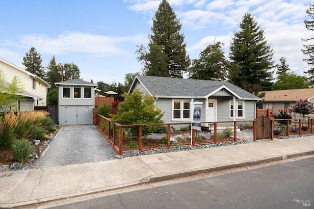 ranch-style house featuring a fenced front yard, a gate, roof with shingles, and gravel driveway