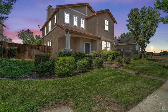 property exterior at dusk featuring a lawn