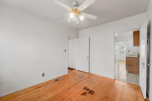 unfurnished bedroom with ceiling fan, sink, and light wood-type flooring