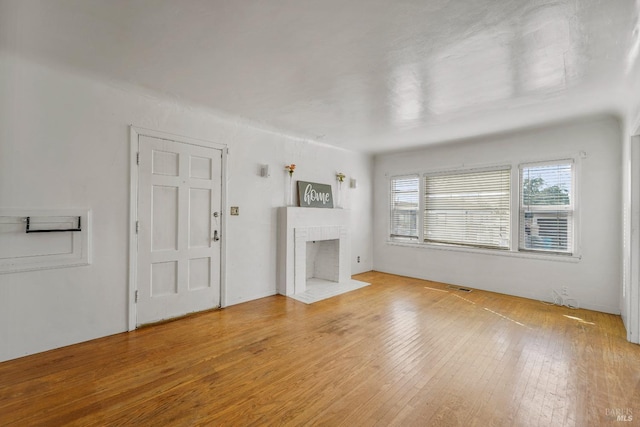 unfurnished living room with a fireplace and light wood-type flooring