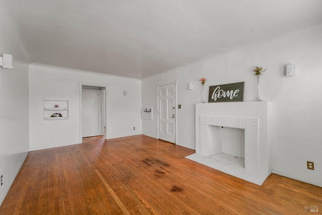 unfurnished living room with hardwood / wood-style flooring and a brick fireplace