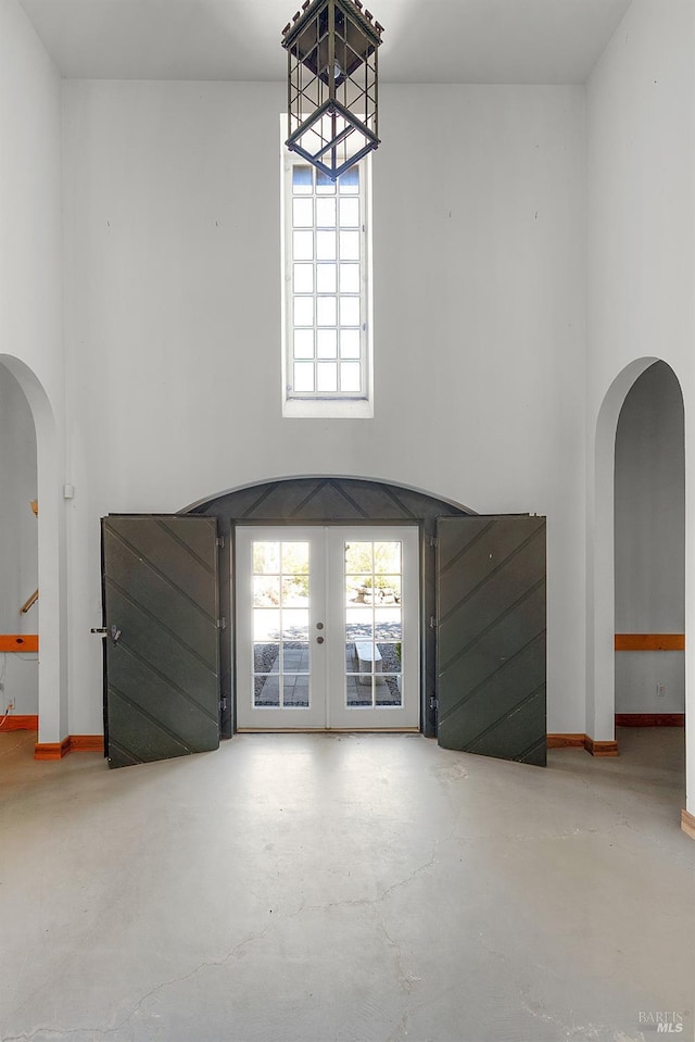 interior space with plenty of natural light, baseboards, arched walkways, and concrete floors