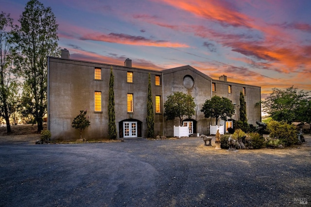 view of front of home featuring french doors, a chimney, and stucco siding