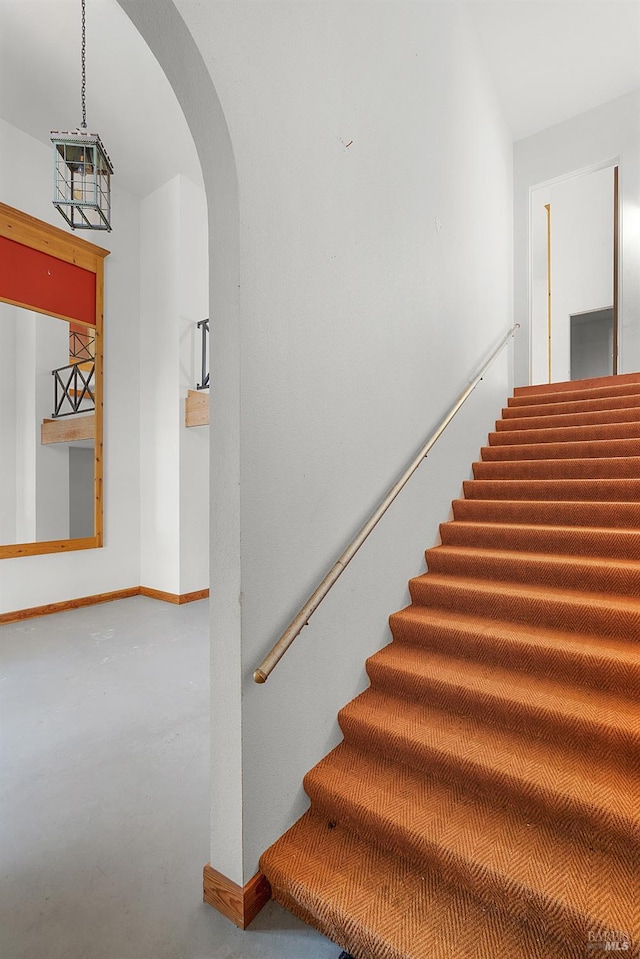 staircase with arched walkways and baseboards