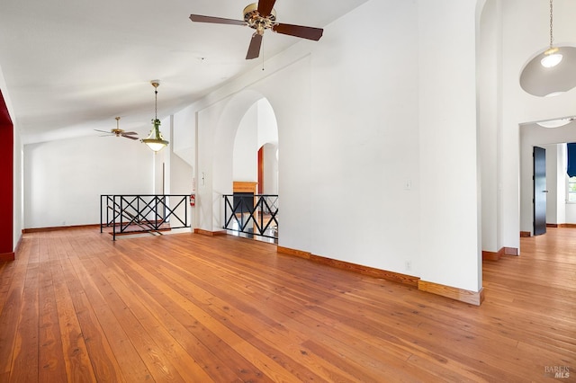 unfurnished room with arched walkways, baseboards, a ceiling fan, and hardwood / wood-style floors