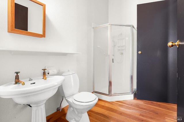 bathroom featuring wood finished floors, toilet, and a stall shower