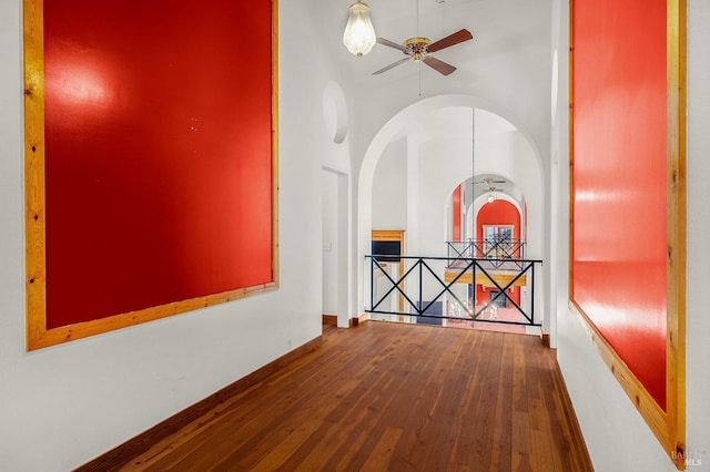 hallway with an upstairs landing, baseboards, and hardwood / wood-style flooring