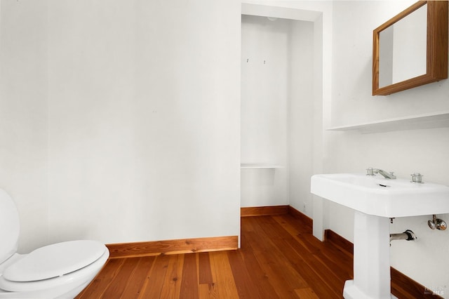 half bathroom featuring toilet, wood finished floors, and baseboards