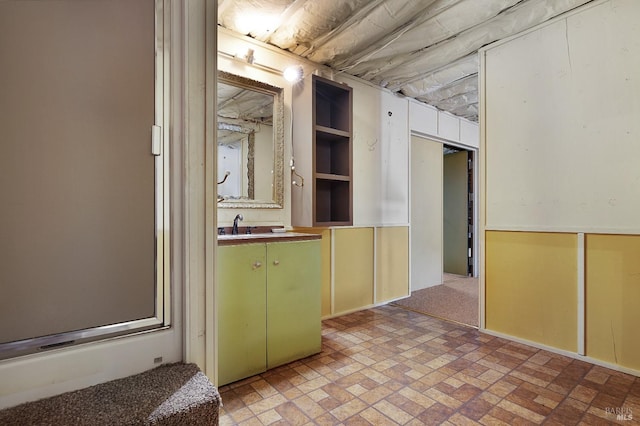 interior space featuring green cabinets, brick floor, and a sink