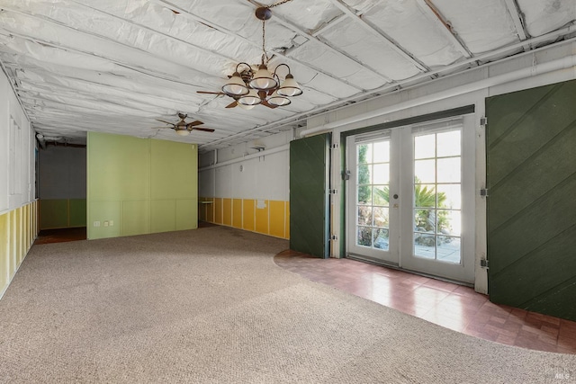 carpeted spare room with ceiling fan with notable chandelier and french doors