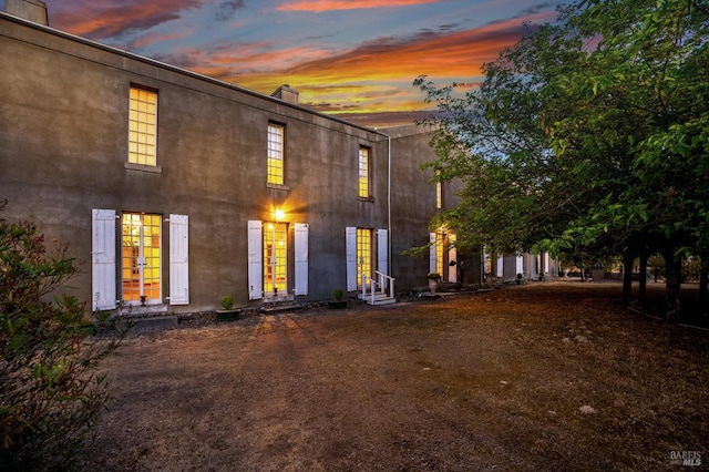 view of front of house with french doors, stucco siding, a chimney, and entry steps