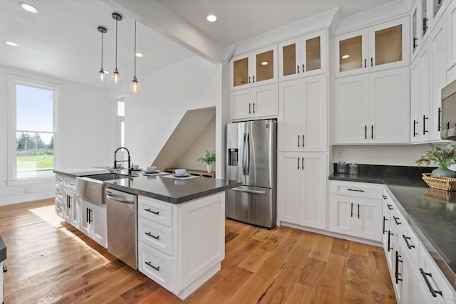 kitchen featuring appliances with stainless steel finishes, sink, pendant lighting, white cabinets, and light hardwood / wood-style floors