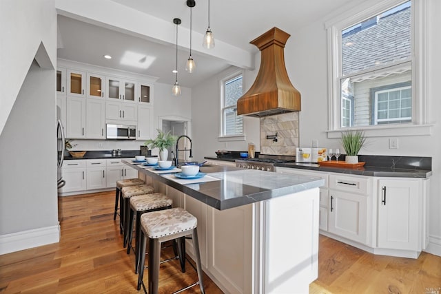 kitchen featuring white cabinets, decorative light fixtures, and a kitchen island with sink