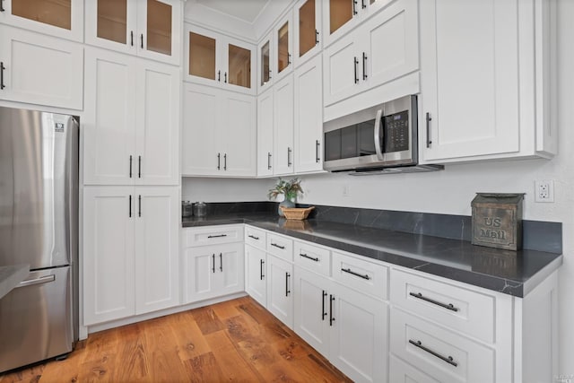 kitchen with light wood-type flooring, stainless steel appliances, and white cabinetry