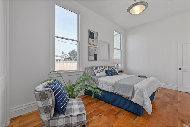 bedroom with light hardwood / wood-style floors and multiple windows