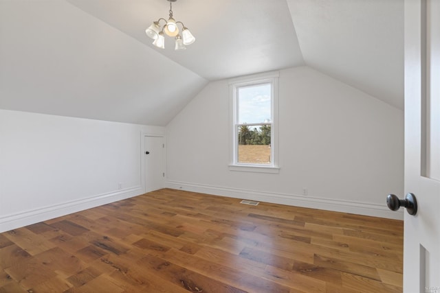 additional living space with hardwood / wood-style floors, lofted ceiling, and a notable chandelier