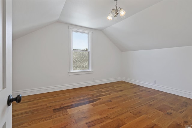 additional living space with a chandelier, wood-type flooring, and lofted ceiling