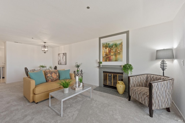 carpeted living room with a chandelier and a brick fireplace