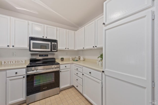 kitchen featuring light tile patterned floors, white cabinetry, lofted ceiling, and stainless steel appliances