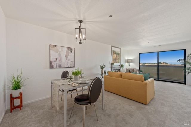 dining area with light carpet, an inviting chandelier, and a textured ceiling