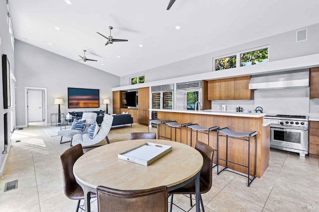 tiled dining space featuring ceiling fan and high vaulted ceiling