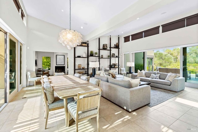 interior space featuring light tile patterned floors, a healthy amount of sunlight, a high ceiling, and a chandelier