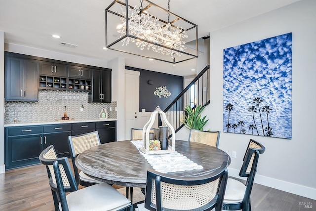 dining space featuring indoor wet bar, dark wood finished floors, visible vents, stairway, and baseboards