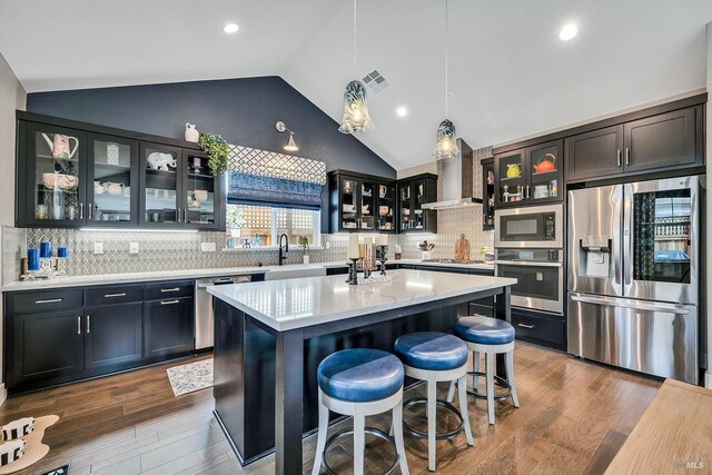 kitchen featuring pendant lighting, stainless steel appliances, vaulted ceiling, and tasteful backsplash