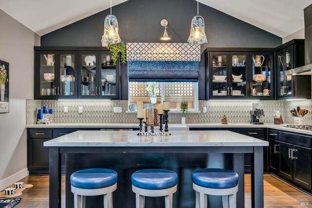 bar featuring wall chimney range hood, pendant lighting, and vaulted ceiling